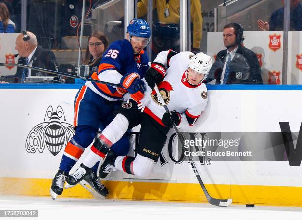 Oliver Wahlstrom of the New York Islanders checks Tim Stutzle of the Ottawa Senators during the first period at UBS Arena on October 26, 2023 in...