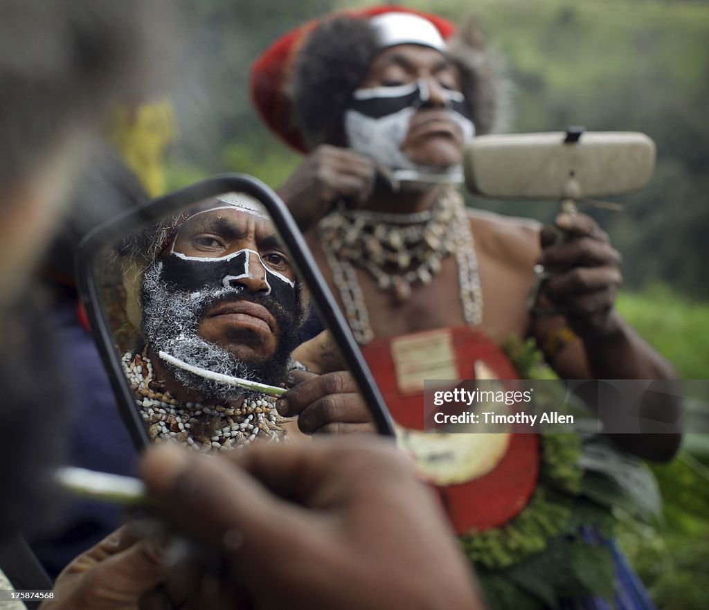 Man apllies tribal face paint in mirror