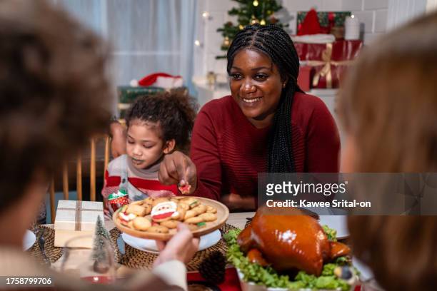 multi-ethnic big family celebrating christmas party together in house. attractive diverse group of people having dinner eating food to celebrate holiday thanksgiving, x-mas eve on dining table at home - thanksgiving golf foto e immagini stock