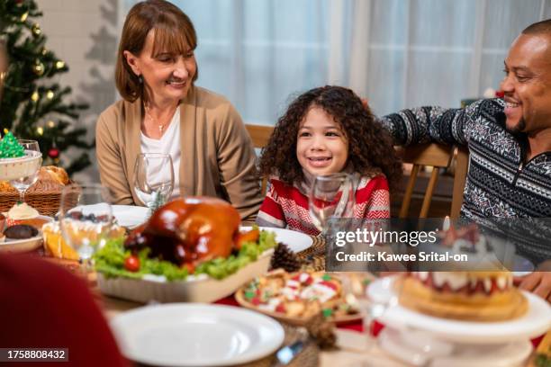 multi-ethnic big family celebrating christmas party together in house. attractive diverse group of people having dinner eating food to celebrate holiday thanksgiving, x-mas eve on dining table at home - thanksgiving golf foto e immagini stock