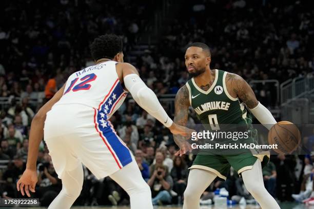 Damian Lillard of the Milwaukee Bucks dribbles the ball against Joel Embiid of the Philadelphia 76ers in the first half at Fiserv Forum on October...