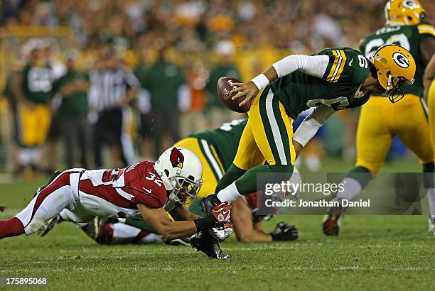 Graham Harrell of the Green Bay Packers is sacked by Tyrann Mathieu of the Arizona Cardinals at Lambeau Field on August 9, 2013 in Green Bay,...