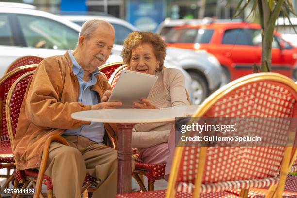 elderly couple looking at the menu on the digital tablet sitting in a cafeteria - free wifi stock pictures, royalty-free photos & images