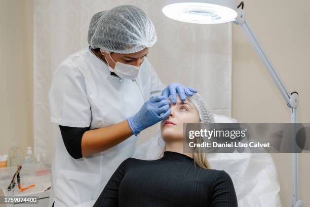 cosmetologist applying permanent make up on eyebrows of woman - durability stock pictures, royalty-free photos & images