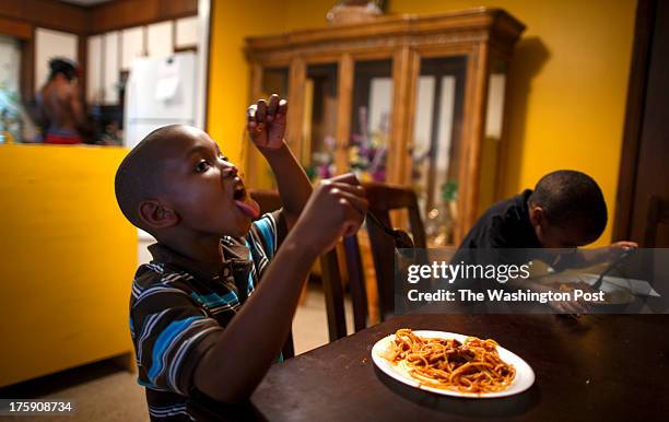 Greensboro, NC - August 7 - Noah Amerson's sons , Malikah Pon Micah Amerson enjoy a spaghetti dinnerat his home in Greensboro, North Carolina...