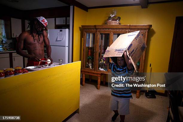 Greensboro, NC - August 7 - Noah Amerson cuts up an onion as he prepares dinner while his son, Malikah Pon plays with a box at his home in...