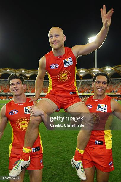 Gary Ablett of the Suns is chaired from the field by team mates Jaeger O'Meara and Harley Bennell after playing his 250th game during the round 20...