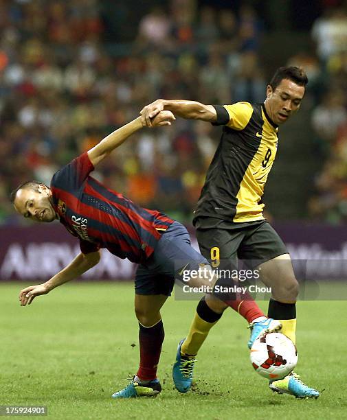 Andres Iniesta of Barcelona FC is tackled by Safiq Rahimi of Malaysia during the friendly match between FC Barcelona and Malaysia at the Shah Alam...