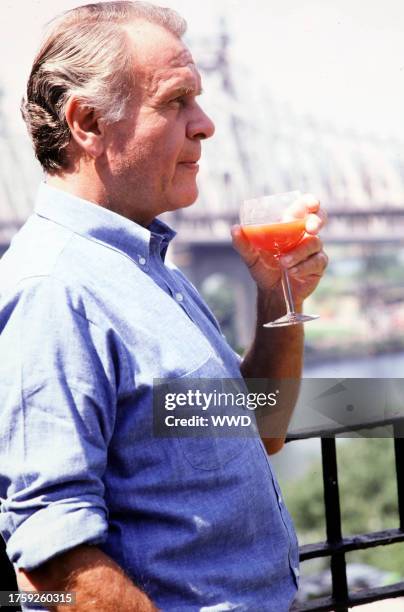 Fashion Designer Bill Blass poses for a portrait sipping a Bloody Mary on the balcony of his penthouse apartment on East 57th Street overlooking the...