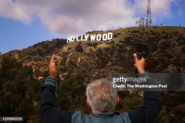 Tourist frames his arms around the iconic Hollywood sign in Los Angeles, California on October 27th, 2023. The sign, which was never meant to be a...
