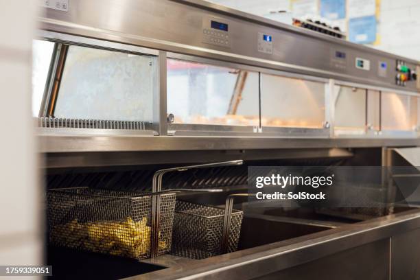 frying chips in the deep fryer - deep fryer stock pictures, royalty-free photos & images