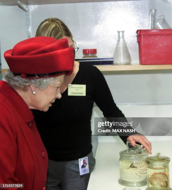 Britain's Queen Elizabeth II looks at mollusc specimens, shown to her by Amelia Campbell, during her visit to the new Darwin Center, which she...