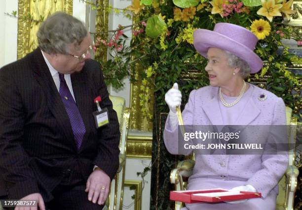 Queen Elizabeth II holds a gold letter opener after it was given to her 12 March 2002, by Sir Patrick Cormack the treasurer of the Commonwealth...