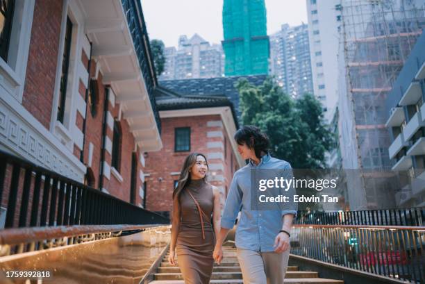 asian chinese couple tourist walking in city street in hong kong - hong kong culture stock pictures, royalty-free photos & images