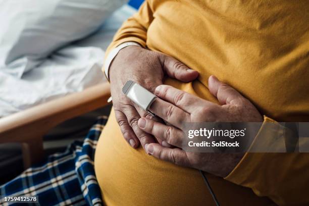 monitoring pulse and oxygen levels affected by health condition - hands on tummy stock pictures, royalty-free photos & images