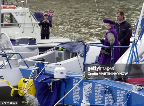 Britain`s Queen Elizabeth II looks on with a happy Pete Goss onboard the catamaran Team Philips, as the champagne bottle smashes against the stern,...