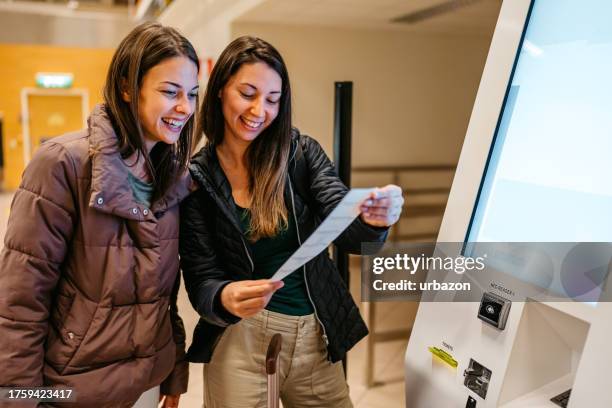 two female friends checking-in their airplane tickets at the airport - input device stock pictures, royalty-free photos & images