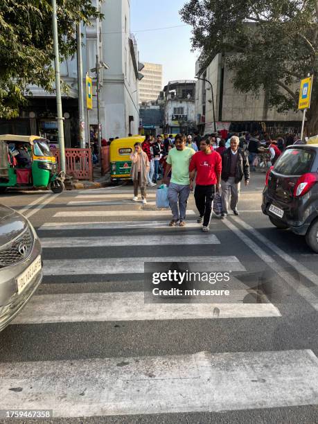image of pedestrians crossing on zebra crossing in front of waiting cars and auto rickshaws, tourists and locals shopping at connaught place, new delhi, india - new delhi business district stock pictures, royalty-free photos & images