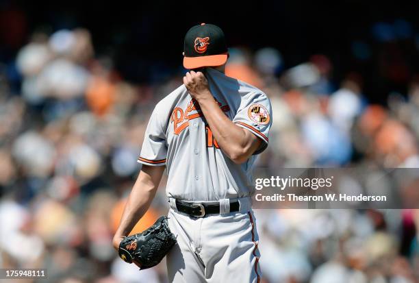 Wei-Yin Chen of the Baltimore Orioles uses his jersey to wipe the sweat off his face after giving up a bases loaded two-run double in the six inning...