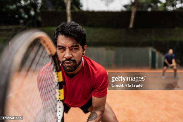 young man playing doubles in a tennis court - sport determination stock pictures, royalty-free photos & images