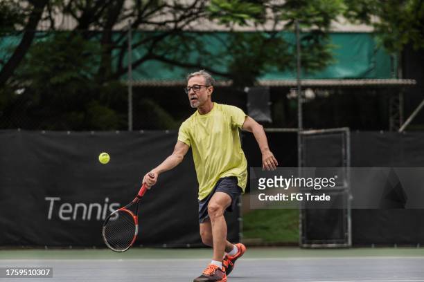 senior man playing tennis - racquet sport stock pictures, royalty-free photos & images