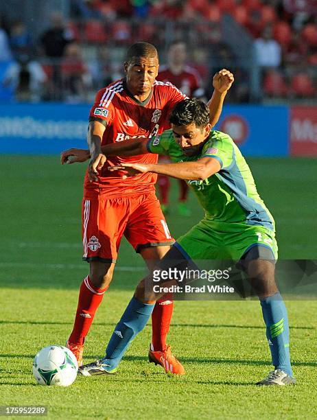 Reggie Lambe of the Toronto FC battles for the ball with Leonardo Gonzalez of the Seattle Sounders FC during MLS game action August 10, 2013 at BMO...