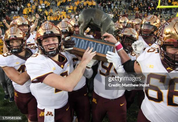 Quarterback Athan Kaliakmanis of the Minnesota Golden Gophers celebrates with teammates as they take the Floyd of Rosedale trophy after their...