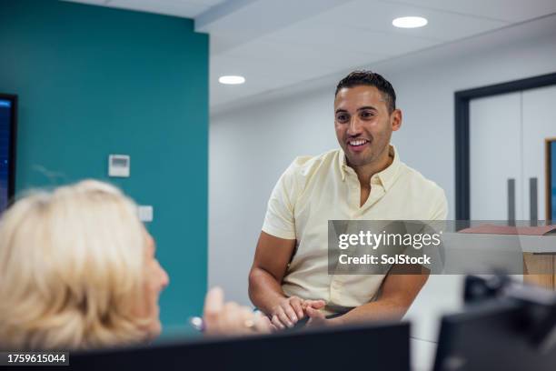quick catch up between patients - male receptionist stock pictures, royalty-free photos & images