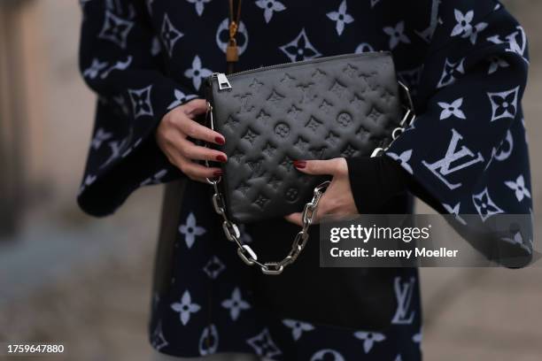 Sonia Lyson seen wearing Louis Vuitton black logo print pattern zip jacket with wide sleeves and Louis Vuitton black logo pattern leather clutch bag...