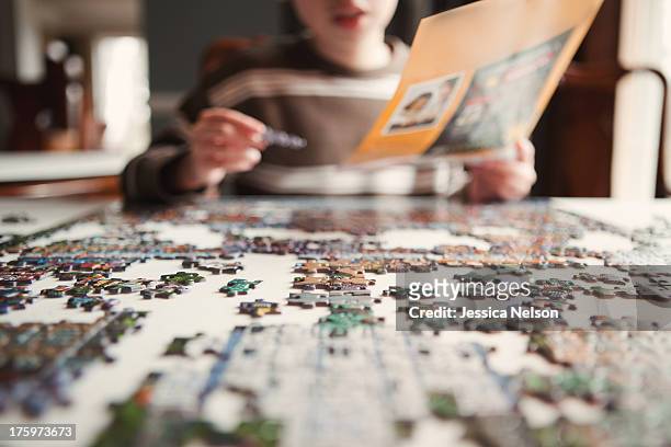 boy working on puzzle - jigsaw puzzle stock-fotos und bilder
