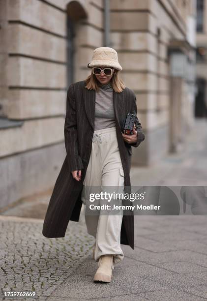 Sonia Lyson seen wearing Louis Vuitton light beige sunglasses, Louis Vuitton light beige fluffy bucket hat, Louis Vuitton Malle colorful clutch bag,...