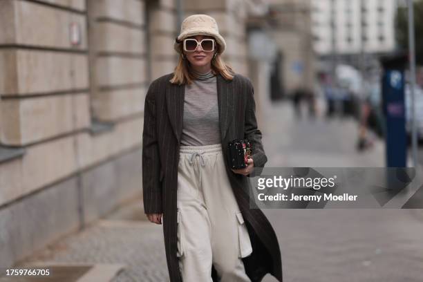 Sonia Lyson seen wearing Louis Vuitton light beige sunglasses, Louis Vuitton light beige fluffy bucket hat, Louis Vuitton Malle colorful clutch bag,...