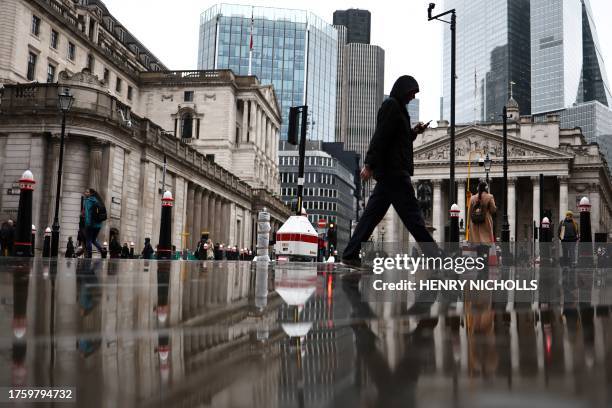 People walk by the Bank of England building and Royal Exchange building , in the financial district, central London, on November 2, 2023.