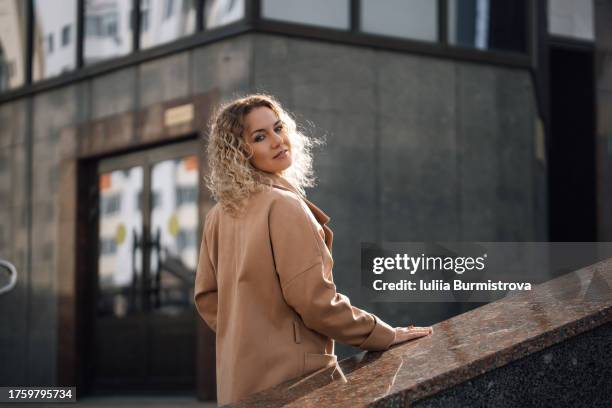 pausing on stairs leading to office building, graceful businesswoman exudes air of confidence and purpose - boss over shoulder stock pictures, royalty-free photos & images