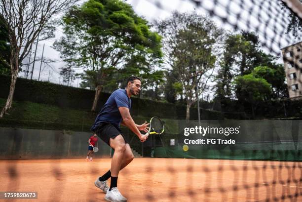 young man playing tennis - tennis net stock pictures, royalty-free photos & images