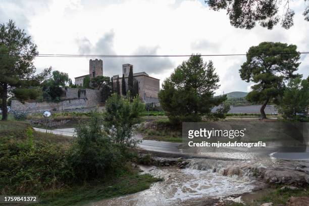 view of a castle on a cloudy and rainy day. sant pere de ribes, barcelona, spain
in the foreground you can see the overflowing water of a river that invades the road - mjrodafotografia stock pictures, royalty-free photos & images