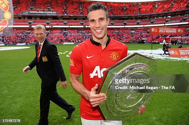 Manchester United manager David Moyes walks behind Robin van Persie as he poses with the trophy after victory in the FA Community Shield match...
