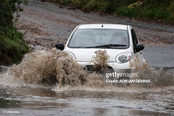 Car drives along a flooded road in Romsey, southern England, on November 2, 2023 as strong winds and heavy rain from Storm Ciaran hit Britain. High...