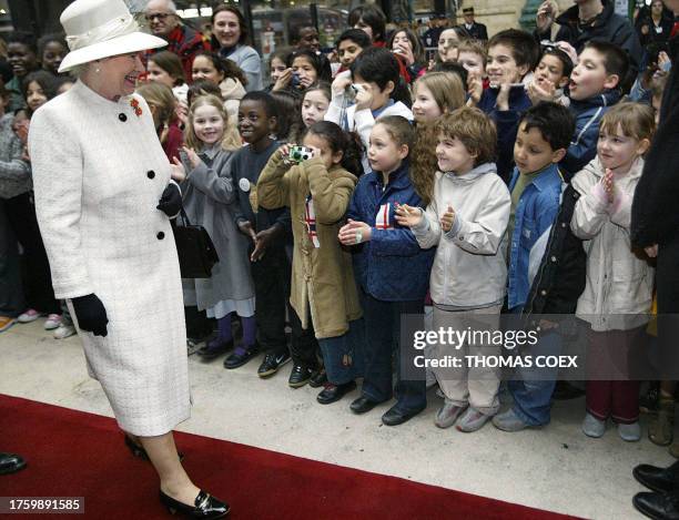 School children greet Queen Elizabeth II as she arrives at the Gare du Nord train station in Paris, 05 April 2004, for the start of a three-day state...