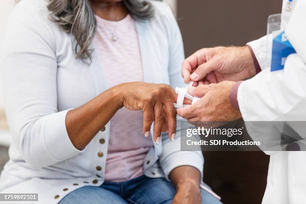 unbekannte patientin bekommt eine schiene an den verletzten finger - verstauchung stock-fotos und bilder