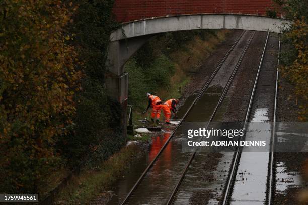 Workers evacuate the water over the flooded railway in Romsey, southern England, on November 2, 2023 as strong winds and heavy rain from Storm Ciaran...