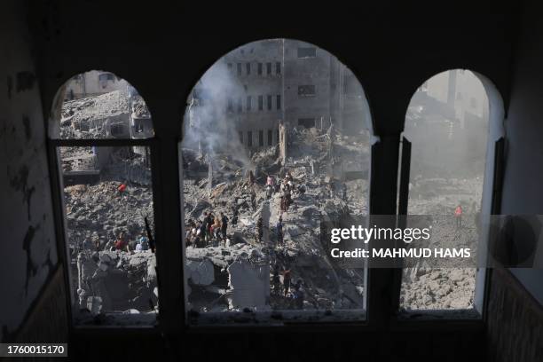 People sift through the smouldering rubble of buildings destroyed in an Israeli strike on the Bureij refugee camp in the central Gaza Strip on...