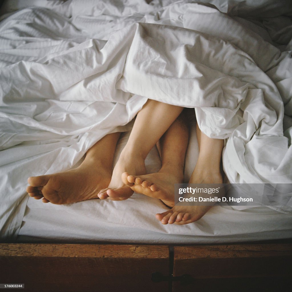 Couple's Feet Entangled in Bed