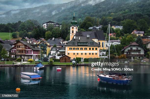scenic view of river by buildings against sky - attersee stock-fotos und bilder
