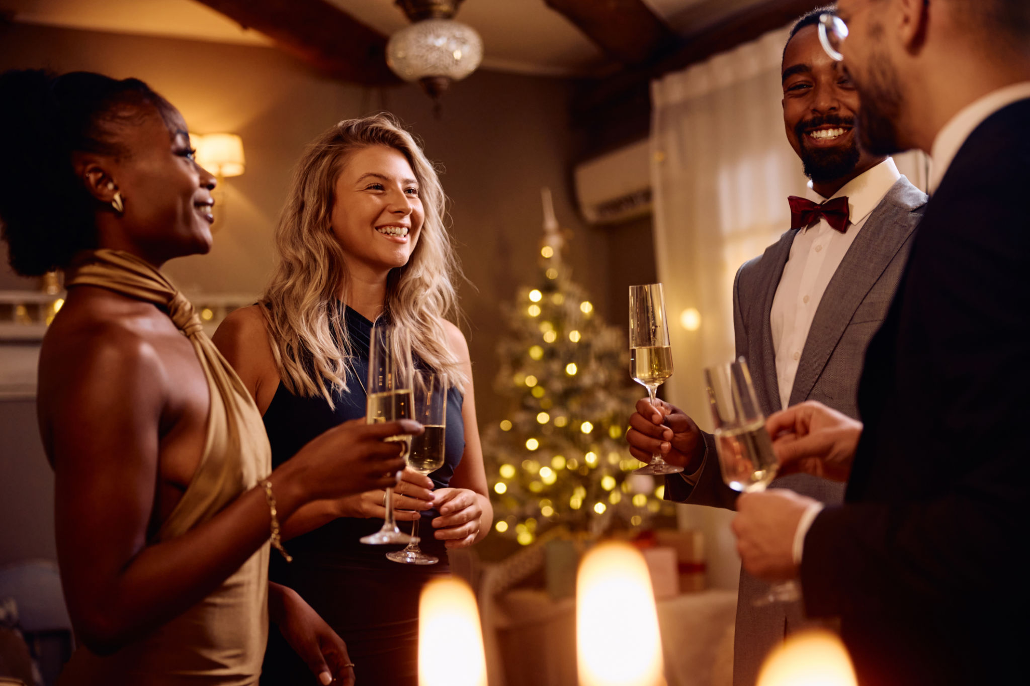 Multiracial group of happy friends drinking champagne and talking on Christmas eve. Multiracial group of happy friends drinking champagne and talking on Christmas eve.