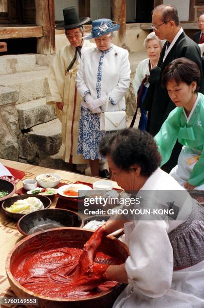 Britain's Queen Elizabeth II watches women make South Korean's main side dish Kimchi as she visits a 400-year-old traditional house in the village of...