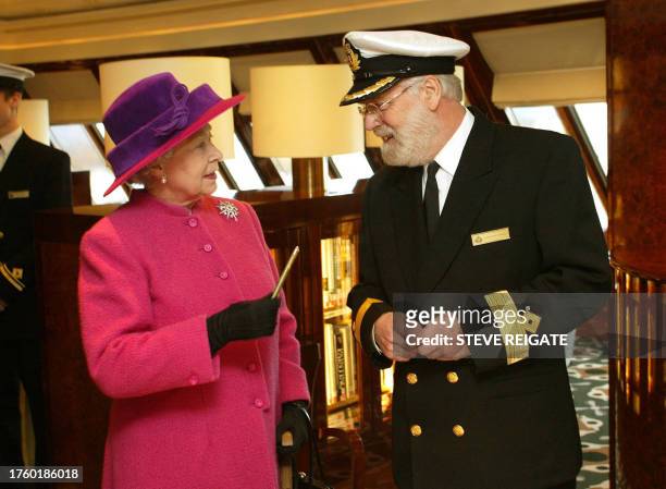 British Queen Elizabeth receives a souvenir pen made of propeller metal from Commodore Ron Warwick during a tour of the bridge at the christening...