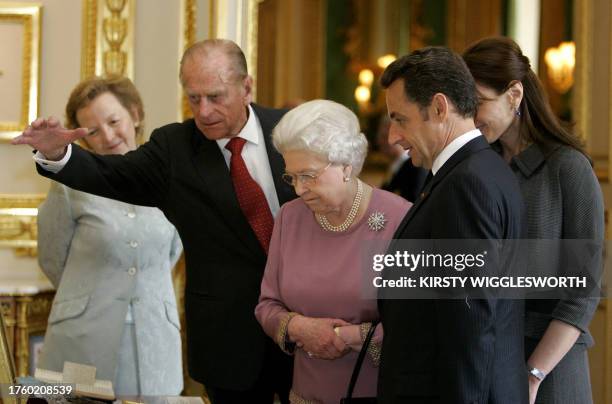 French President Nicolas Sarkozy and his wife Carla Bruni-Sarkozy are shown items from the Royal Collection by Britain's Queen Elizabeth II and...