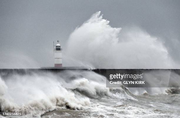 Waves crash over Newhaven Lighthouse and the harbour wall in Newhaven, southern England on November 2 as strong winds and heavy rain from Storm...
