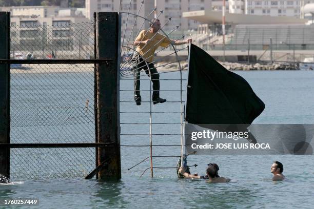 Members of the ecologist group " Ecologists in action " hang a black flag on a fence on Spain's border with Gibraltar 10 July 2004 to protest against...